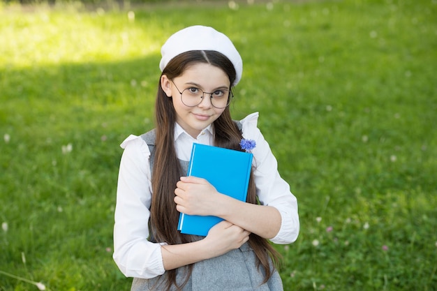 Elegante Schulmädchen-Kindermädchenstudie mit Buch im Park, Lernkonzept.