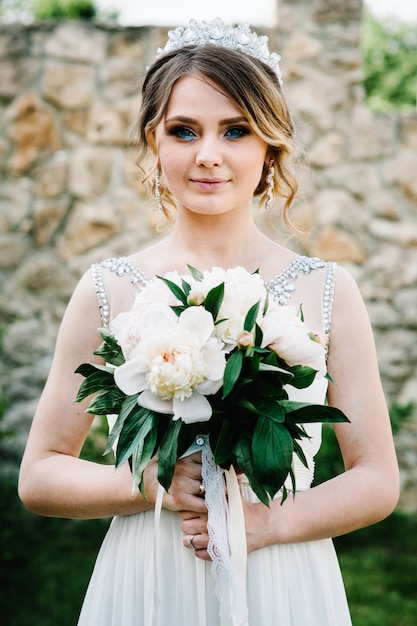 Elegante sonrisa feliz novia con ramo de peonías. Naturaleza.