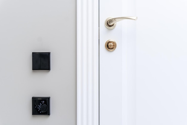 Elegante tirador de puerta de bronce y cerradura en una nueva puerta interior blanca