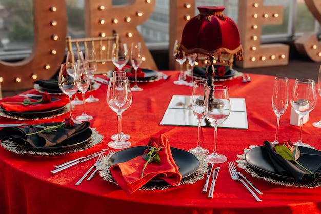 Elegante Tischdeko rote Tischdecke Teller mit Servietten und frische Rosen Gläser Besteck