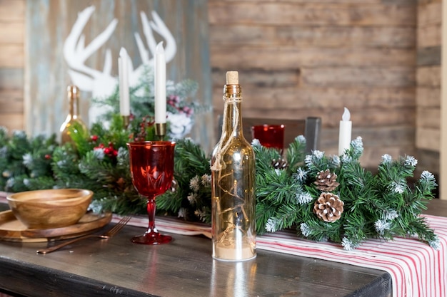 Elegante Tischdekoration für das Weihnachtsessen Dekoration von Weihnachtstischkerzen Wacholderzweigen und Servietten Holzplatten Neujahrsdekorationen im Wohnzimmer im Landhausstil