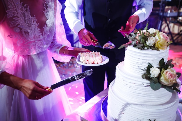Elegante und stilvolle Hochzeitstorte mit Blumen Jungvermählten stehen in der Nähe einer großen Hochzeitstorte