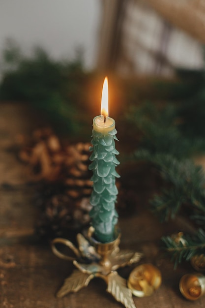 Elegante vela de natal como abeto e sinos dourados sobre fundo de galhos na mesa rústica