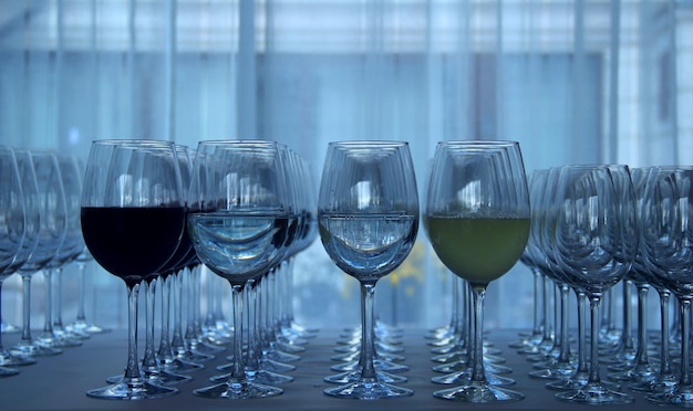 Elegante Weingläser aus Kristall, aufgereiht auf dem weißen Tisch