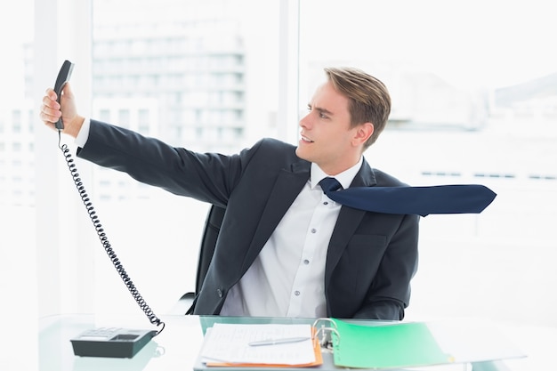 Eleganter Geschäftsmann, der heraus Telefon im Büro hält