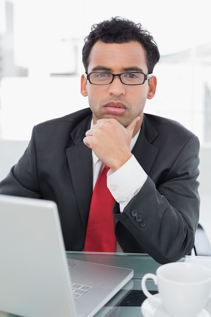 Eleganter Geschäftsmann mit Laptop am Schreibtisch