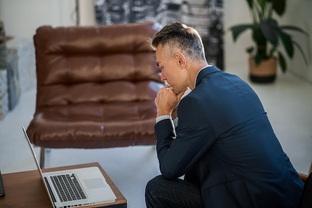 Eleganter, gutaussehender Mann in einem Anzug, der im Büro arbeitet