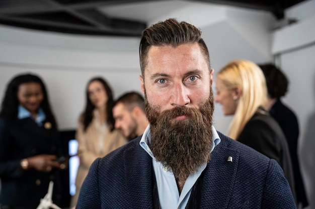 Eleganter Hipster-Geschäftsmann, der in einem modernen Büro mit dem multiethnischen Team hinter ihm arbeitet Konzept der Führung und Teamarbeit, um Ziele zu erreichen Konzentrieren Sie sich auf die Augen