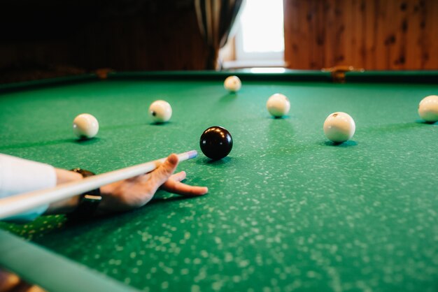 Eleganter junger Mann im dunklen Anzug spielt Billard