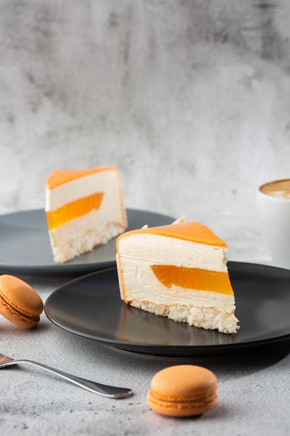 Eleganter Kuchen mit Kokosnuss, Passionsfrucht, Mangos und Bananen, überzogen mit Schokoladenglasur. Scheibe Orangenschichtkuchen auf Marmorhintergrund. Tapete für Konditorei oder Cafémenü. Vertikale.