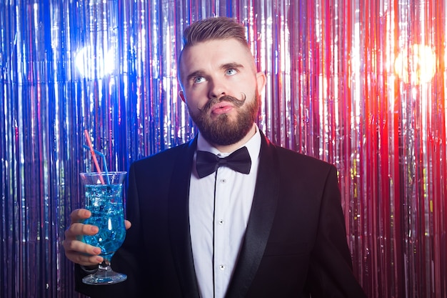 Eleganter Mann im Anzug, der einen Cocktail hält