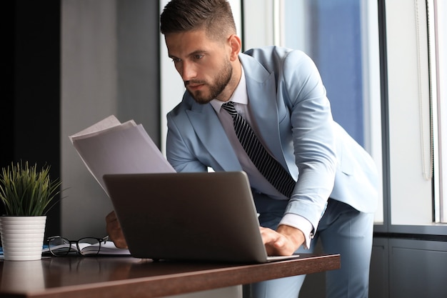 Eleganter moderner geschäftsmann, der daten während der arbeit im büro analysiert.