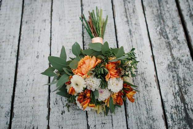 Eleganter orange und weißer Hochzeitsblumenstrauß auf hölzernem.
