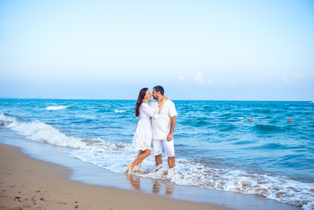 Eleganter und attraktiver glücklicher Familienmann und -frau, die an der Seeküste spazieren gehen. Junge Frau und Ehemann in der Liebe.