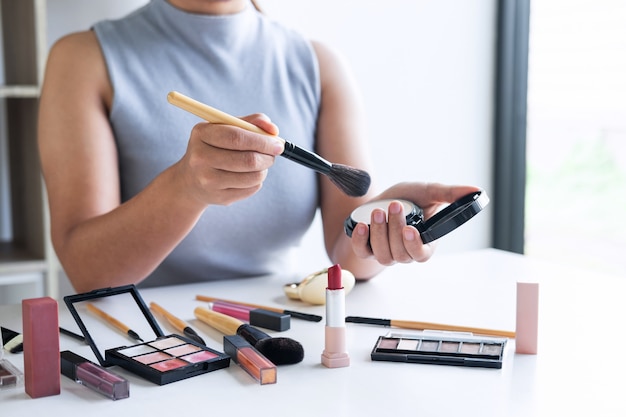 Eleganter weiblicher Schönheitsblogger, der Prüfungsschönheitskosmetik unter Verwendung der Produktmake-up-Tutorenkosmetik und des Verkaufsprodukts zeigt