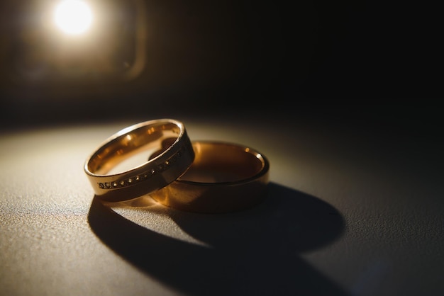 Elegantes anillos de boda para la novia y el novio en un fondo negro con reflejos, macro, enfoque selectivo