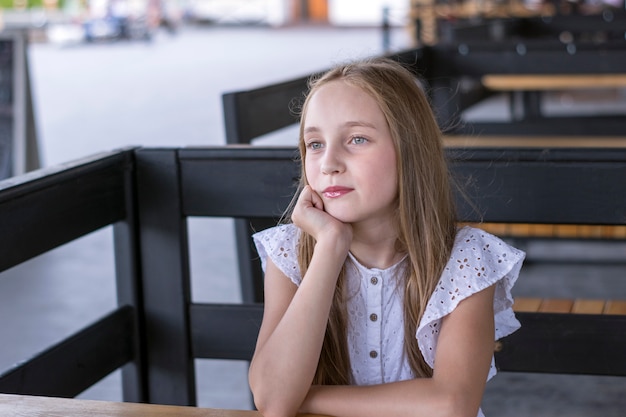 Elegantes blondes Modell, das allein am Café sitzt