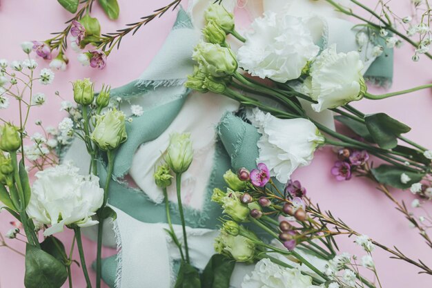 Foto elegantes cintas de seda y hermosas flores tiernas sobre fondo rosa plano lay feliz día de la mujer y concepto del día de la madre tarjeta de felicitación floral o pancarta