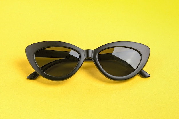 Elegantes gafas de sol negras aisladas en amarillo