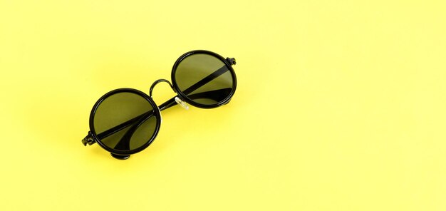 Elegantes gafas de sol negras aisladas en la vista superior de fondo amarillo Concepto de verano