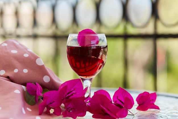 Elegantes Glas Rotwein Dekorative rosa Blüten von Bougainvillea in einem Glas Romantisches Konzept