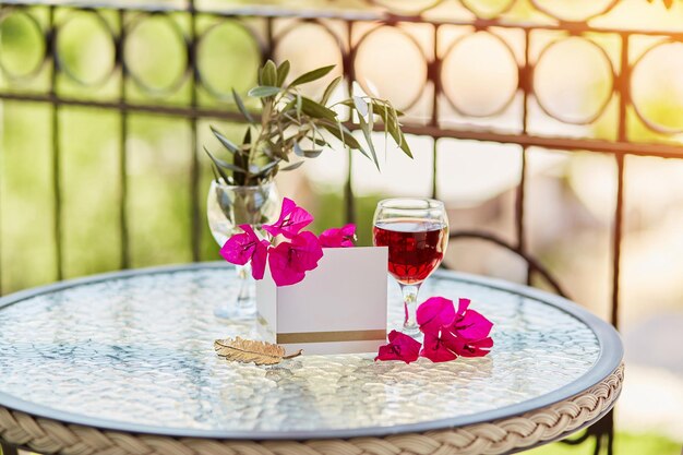 Elegantes Glas Rotwein Dekorative rosa Blüten von Bougainvillea Mock-up von Postkarten oder Einladungen