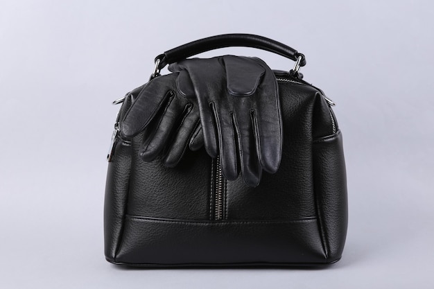 Foto elegantes guantes de cuero negro y bolso de mano sobre fondo gris