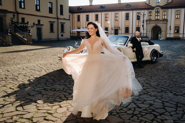 Elegantes Hochzeitspaar Im Innenhof des Schlosses in der Nähe eines Retro-Autos