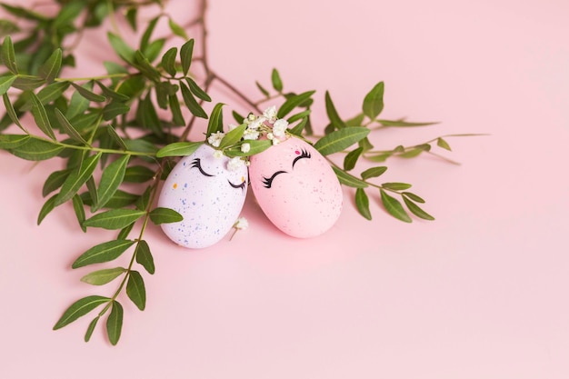 Foto elegantes huevos de color rosa y liliacos de pascua con caras lindas en coronas florales fondo rosa concepto de pascua feliz copiar espacio aislado