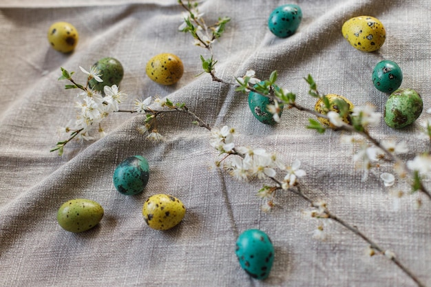 Elegantes huevos de pascua y flores de cerezo en flor en una mesa rústica Felices Pascuas Bodegón rústico de pascua Huevos de codorniz pintados naturales y flores de cerezo en tela de lino