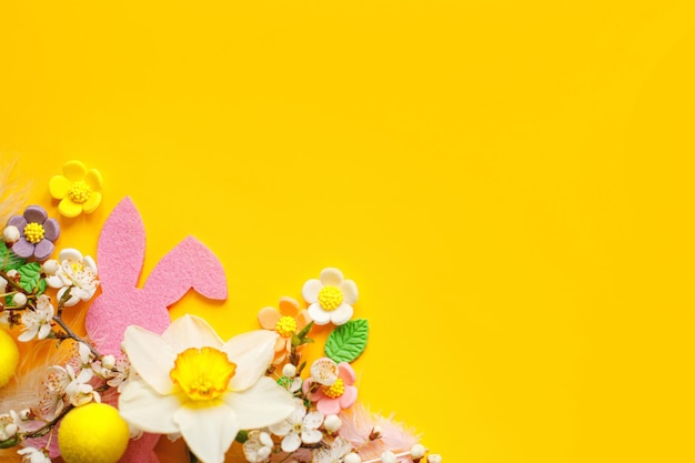 Elegantes huevos de Pascua flores conejito y flores de cerezo planas sobre fondo amarillo con espacio de copia Plantilla de tarjeta de felicitación de Pascua feliz Banner de primavera moderno