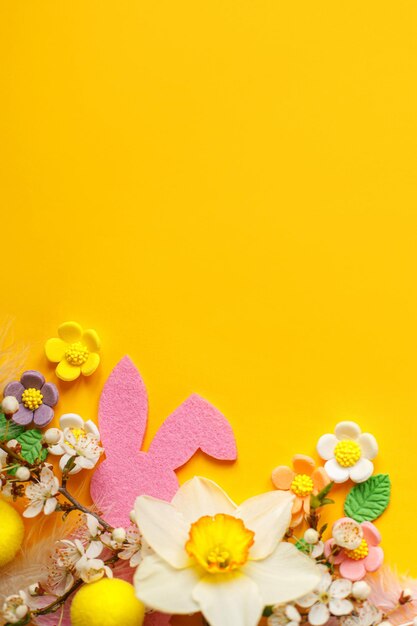 Elegantes huevos de Pascua flores conejito y flores de cerezo planas sobre fondo amarillo con espacio de copia Plantilla de tarjeta de felicitación de Pascua feliz Banner de primavera moderno