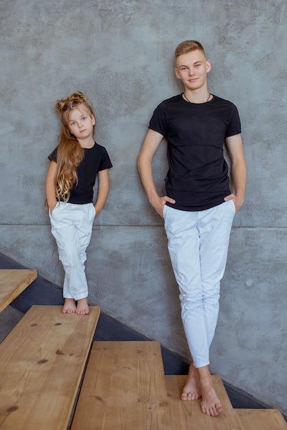 Elegantes irmãos caucasianos irmão e irmã em camiseta preta e calça branca em pé