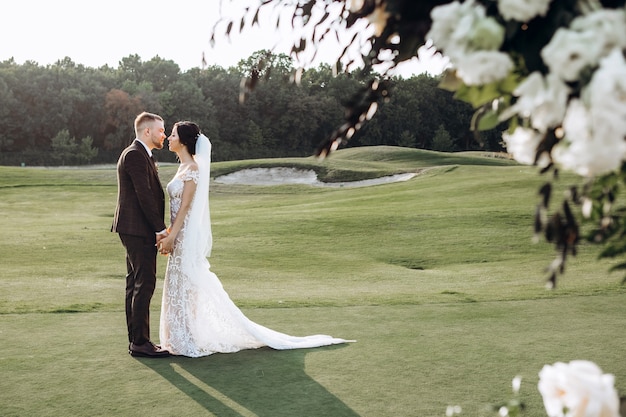 Elegantes Paar, das bei Sonnenuntergang, Liebesgeschichte, Porträt von Braut und Bräutigam am Hochzeitstag geht