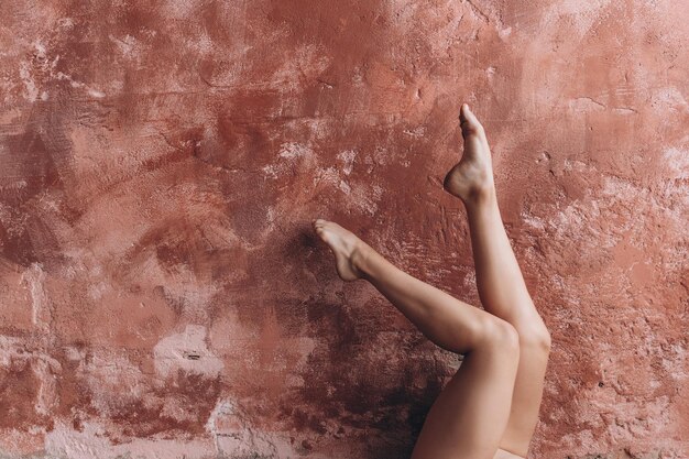 Elegantes piernas femeninas Una niña realiza ejercicios gimnásticos levantando sus hermosas piernas bronceadas