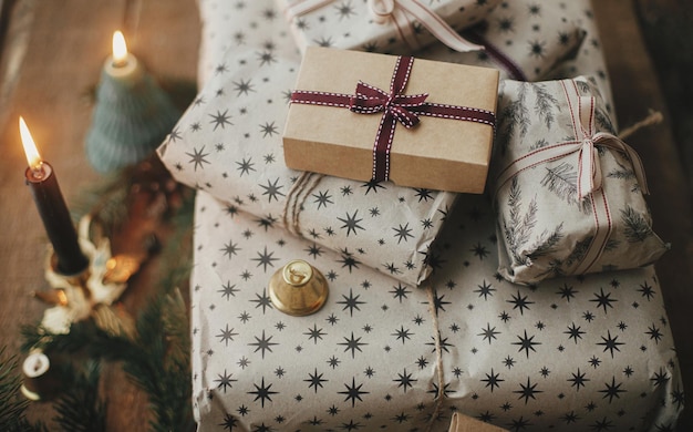 Elegantes regalos de navidad envueltos en ramas de abeto de vela de papel en madera rústica Feliz Navidad