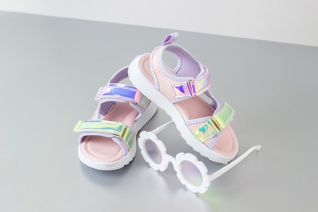 Elegantes sandalias holográficas para niños sobre fondo gris Zapatos de verano de moda brillante