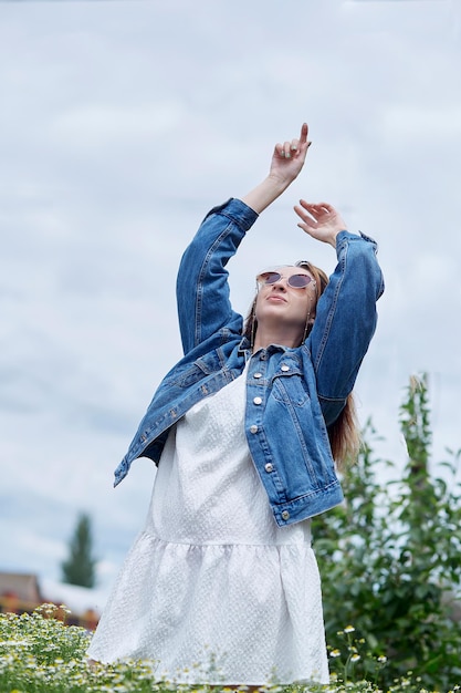 Elegantes, sinnliches, tausendjähriges Mädchen auf dem entspannenden Kamillenfeld Verbindung mit der Natur Sommerästhetik