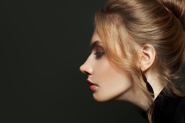 Elegantes weibliches Profil Junge blonde Frau auf schwarzem Hintergrund schönes Gesicht aus der Nähe