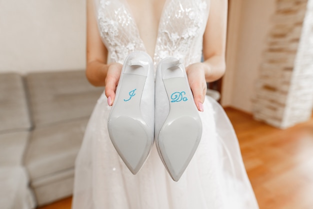 Eleganz Brautschuhe mit der Aufschrift "I do" hautnah. weiße Schuhe der hohen Absätze in den Händen der Frau. Hochzeitstag