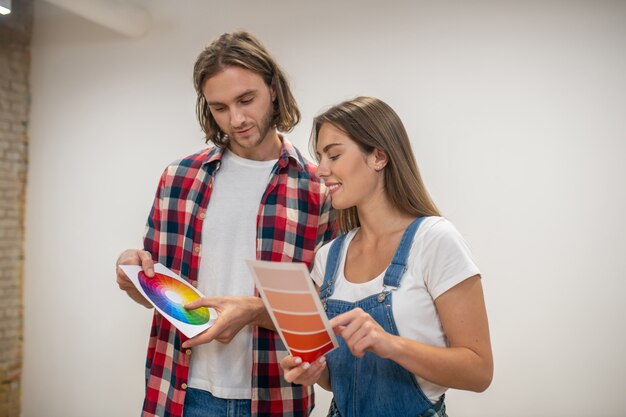 Foto elegir color. pareja joven discutiendo el color de las paredes y mirando involucrado