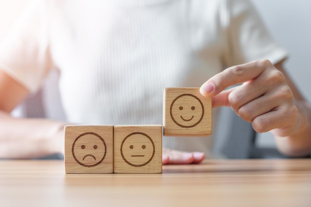 Elegir a mano la cara sonriente del bloque Emoción para la revisión del cliente buena experiencia retroalimentación positiva encuesta de satisfacción evaluación estado de ánimo concepto del día mundial de la salud mental