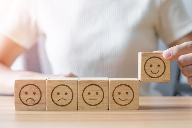 Elegir a mano la cara sonriente del bloque Emoción revisión del cliente buena experiencia retroalimentación positiva encuesta de satisfacción evaluación del servicio estado de ánimo concepto del día mundial de la salud mental