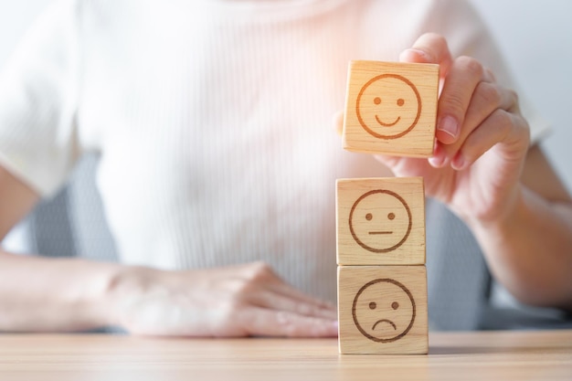 Elegir a mano la cara sonriente del bloque Emoción revisión del cliente buena experiencia retroalimentación positiva encuesta de satisfacción evaluación del servicio estado de ánimo concepto del día mundial de la salud mental