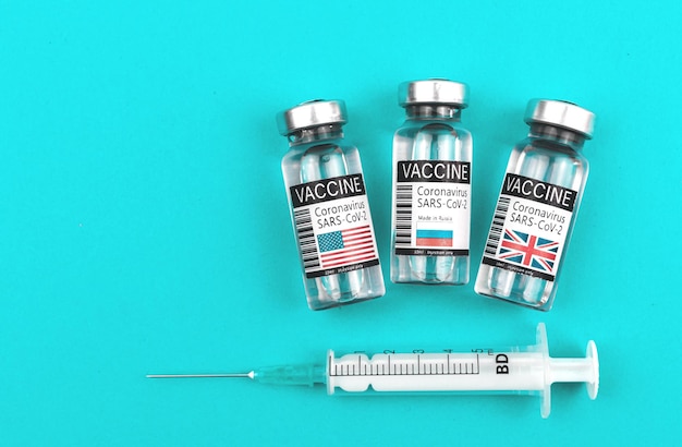 Elegir la mejor vacuna de EE. UU., Reino Unido o Rusia, viales de vacuna COVID-19 con banderas de países, antecedentes médicos y de concepto de vacunación con foto de jeringa