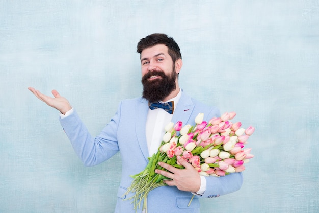 Elegir y pedir regalo Hombre barbudo con regalo de flores frescas Hipster feliz con ramo de tulipanes Regalo floral para el día de San Valentín Regalo de San Valentín para mujeres Hombre de San Valentín con la mano vacía para copiar espacio