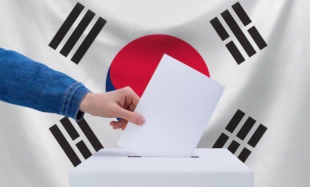 Eleições na Coreia do Sul O conceito de eleições Uma mão joga uma cédula nas urnas