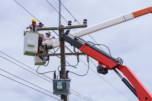 Elektriker arbeitet an einem Eimerwagen, um Hochspannungsleitungen zu warten.