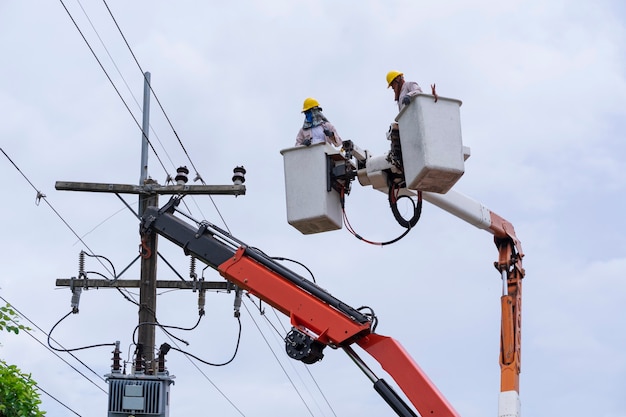 Elektriker arbeitet an einem Eimerwagen, um Hochspannungsleitungen zu warten.