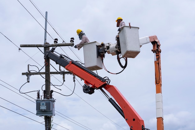 Elektriker arbeitet an einem Eimerwagen, um Hochspannungsleitungen zu warten.